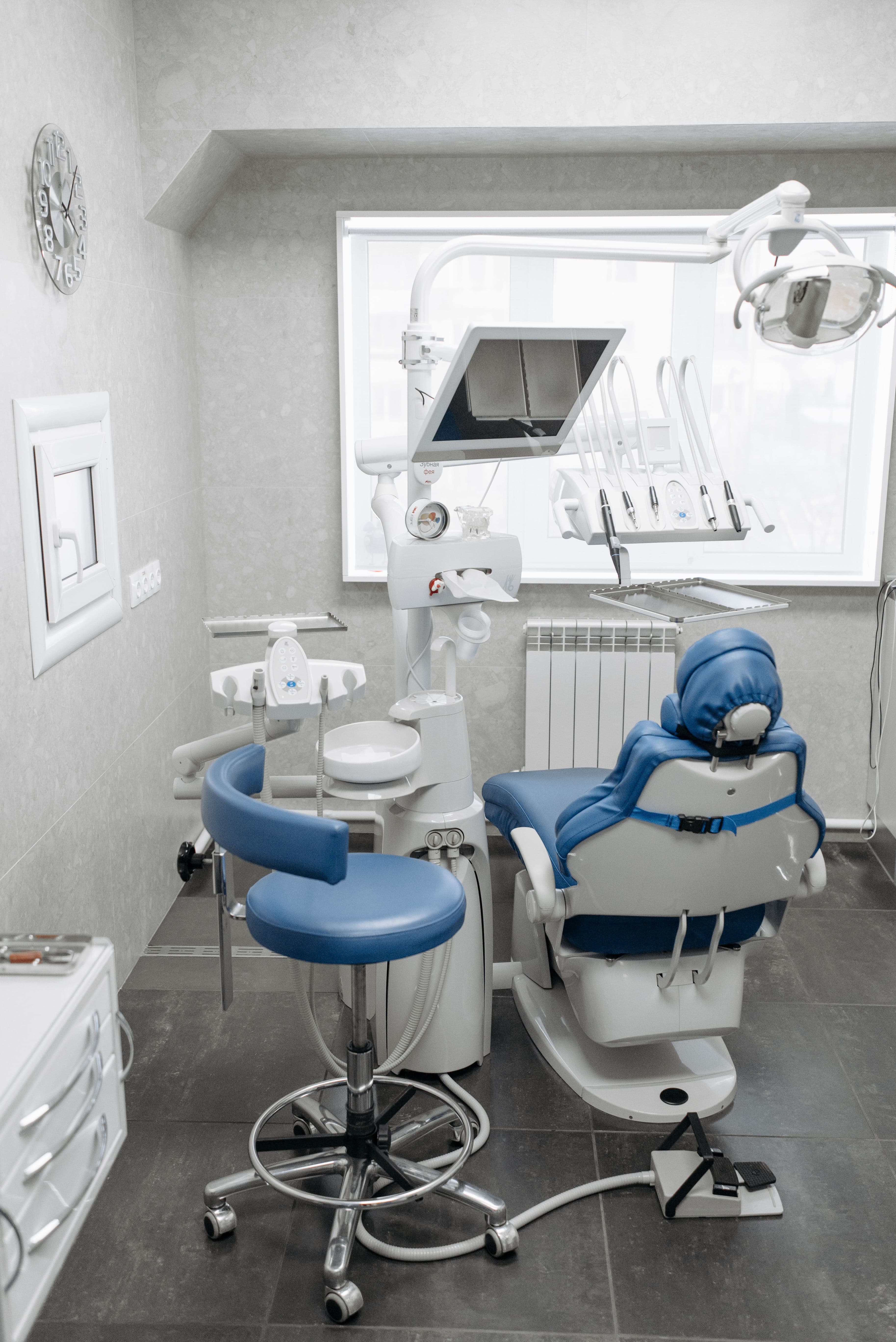 A modern, spotless treatment room with a blue examination chair and overhead light