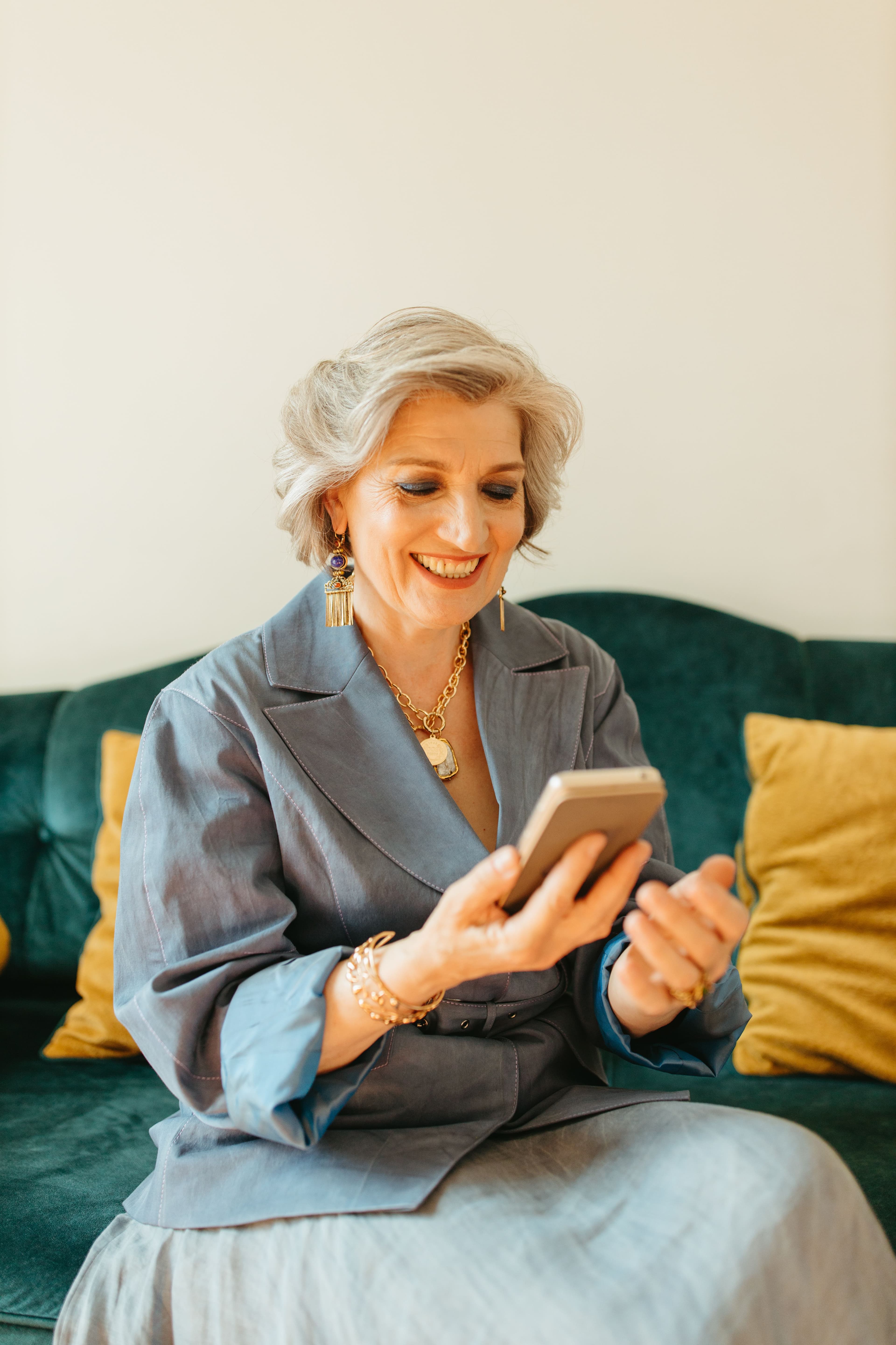 A patient smiling at her phone as she messages the clinic on WhatsApp from her sofa at home